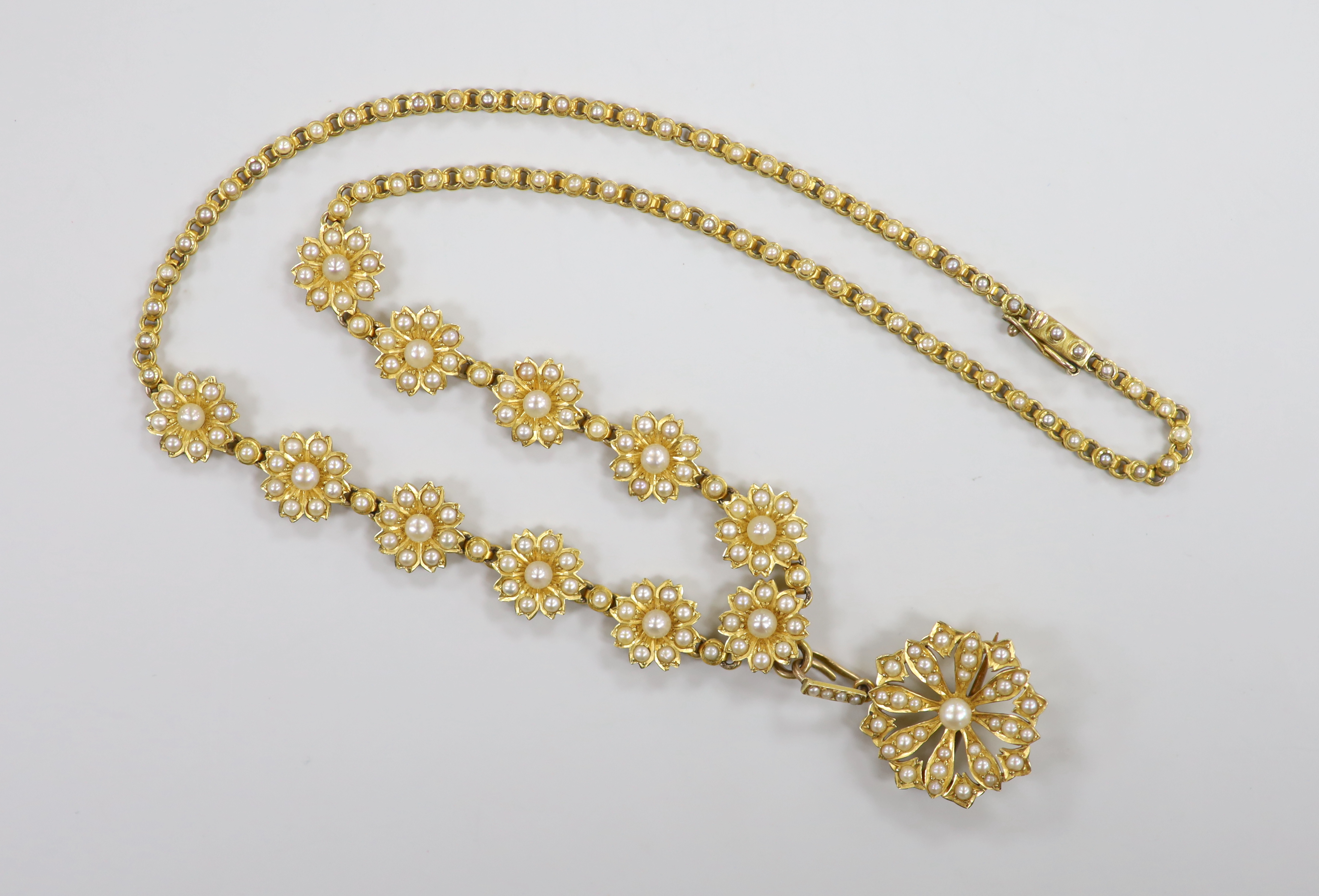 An Edwardian yellow metal and seed pearl set pendant brooch necklace, with flower head motifs, 43cm, gross weight 23.4 grams.